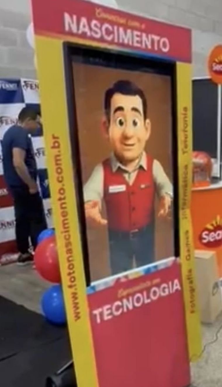 O totem da Foto Nascimento no BDXP 2025: uma tela vertical com o avatar Nascimento, de colete vermelho, na moldura escrita Converse com o Nascimento.